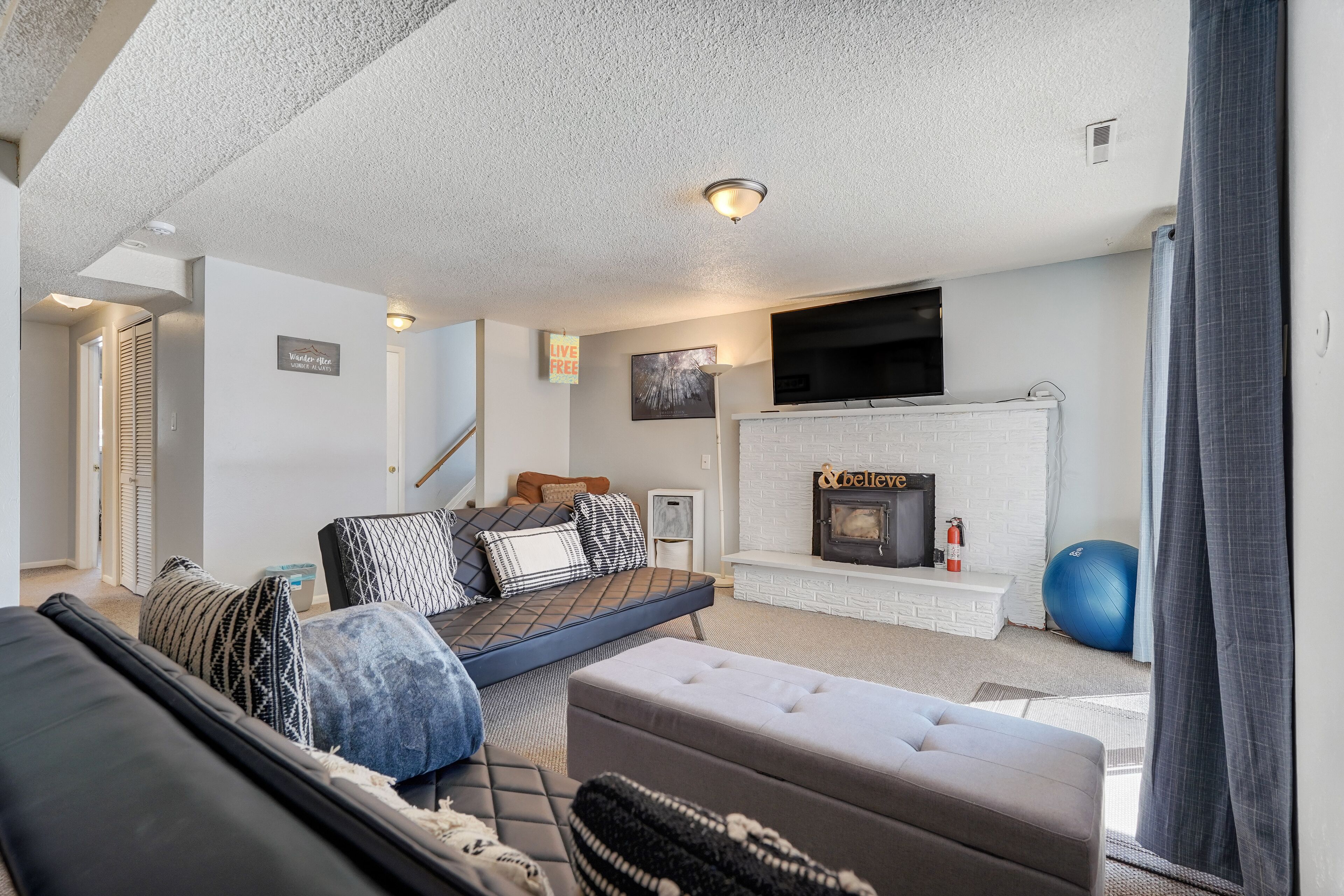 A modern living room with a sofa, ottoman, and a fireplace.