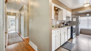 A kitchen with white cabinets, a tiled backsplash, and a refrigerator. - Always Somerset (Colorado Springs)