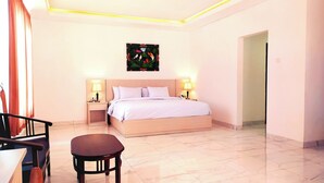 Une chambre d’hôtel avec un lit, des lampes de chevet, une petite table et un tableau au mur.