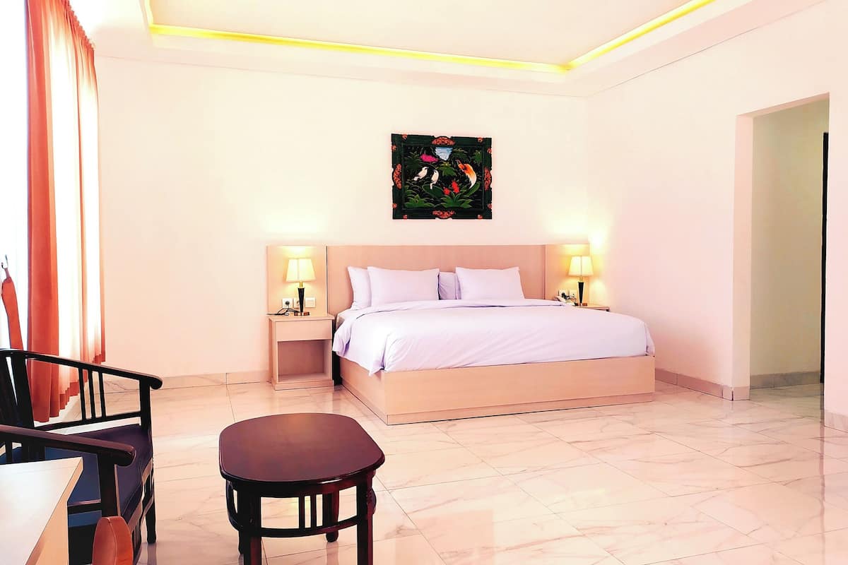Ein Hotelzimmer mit Bett, Nachttischlampen, einem kleinen Tisch und einem Bild an der Wand.