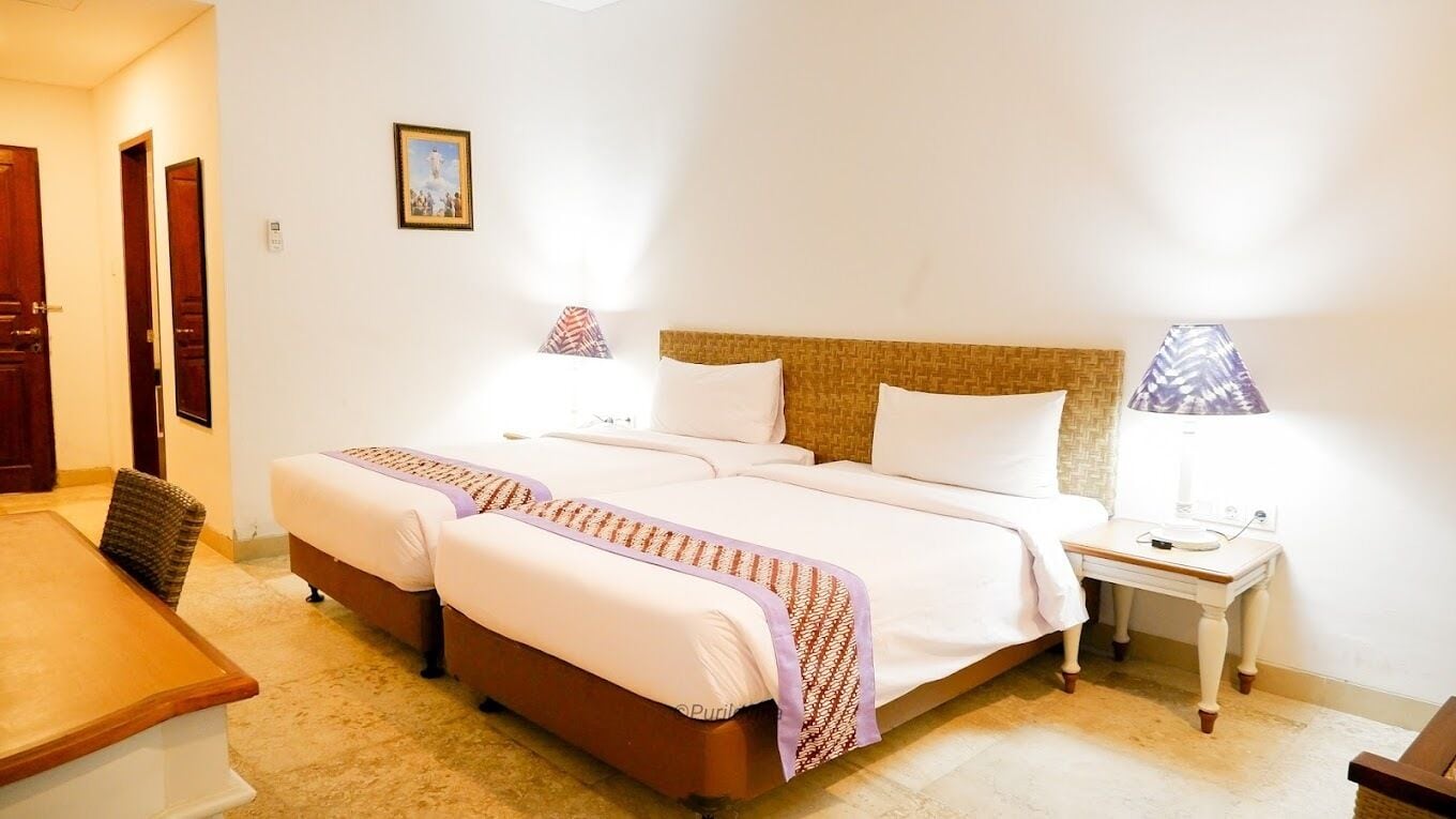 Habitación de hotel con una cama doble, una mesita de noche, una lámpara y un cuadro en la pared.