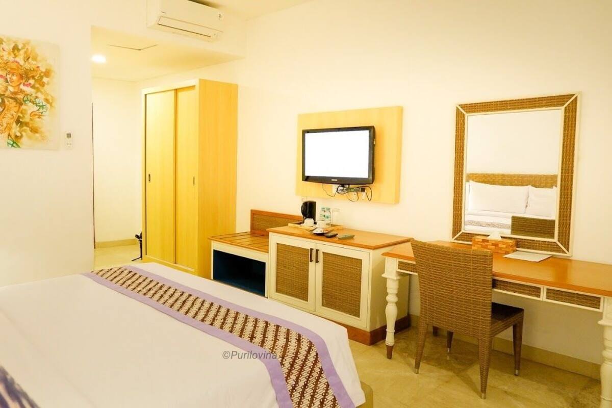 Ein Hotelzimmer mit Bett, Schreibtisch, Stuhl, Fernseher und Kleiderschrank.