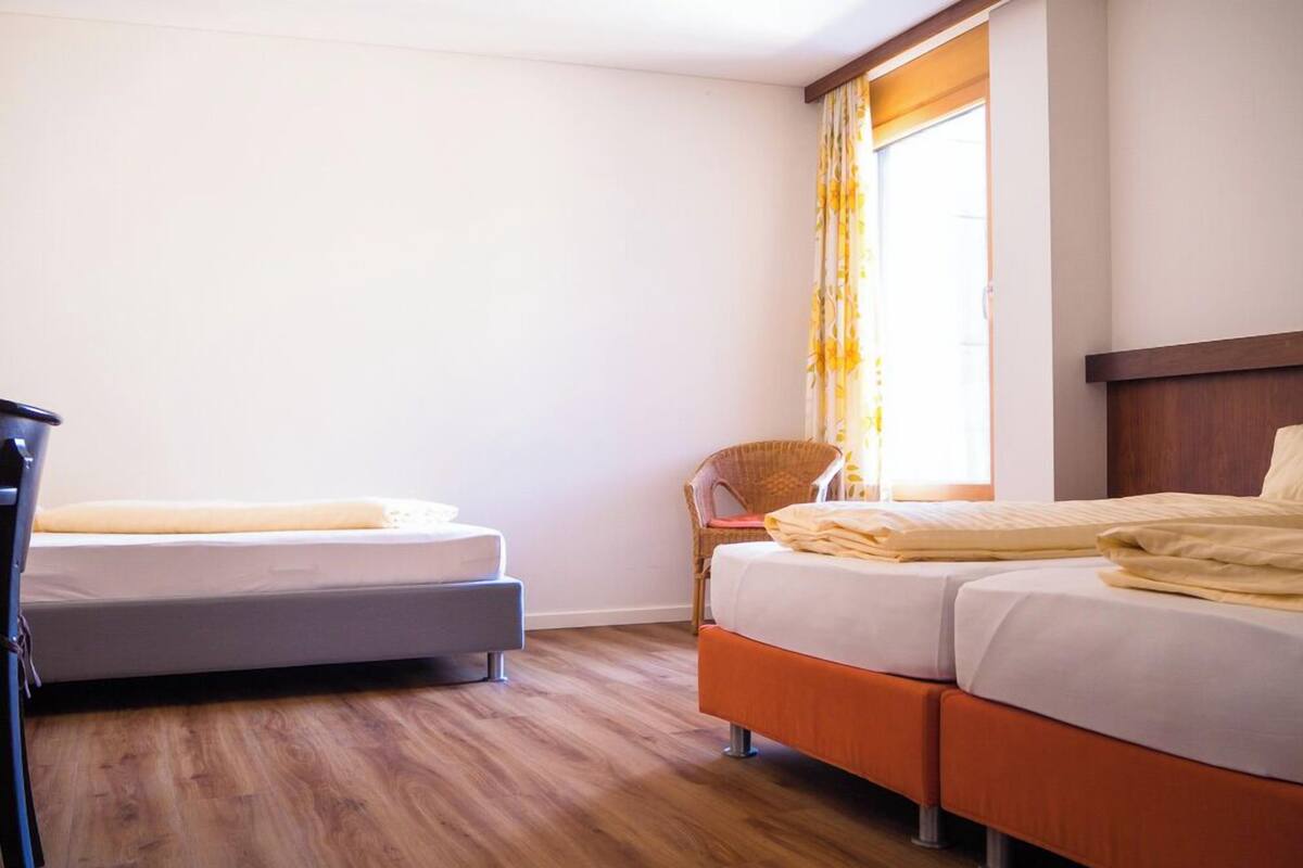 Ein Hotelzimmer mit zwei Betten, einem Sessel und einem Schreibtisch.