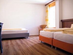 Une chambre d’hôtel avec deux lits, une chaise et un bureau.