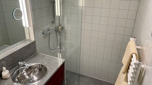 Bagno con lavabo su piano in granito, specchio, doccetta e porta asciugamani.