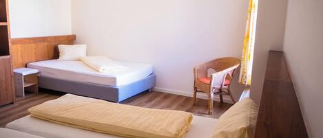 A bedroom with a bed, a chair, and a wooden wardrobe.