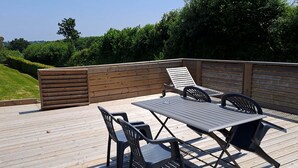 An outdoor deck with a wooden table and chairs, surrounded by a wooden fence.