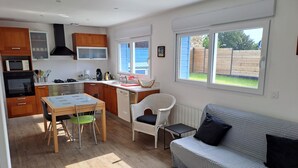 A modern kitchen with wooden cabinets, a dining table, and a sofa.