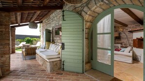 A cozy outdoor seating area with a stone wall, a green door, and a white sofa. - Nice home in Sveti Lovrec (Sveti Lovrec)
