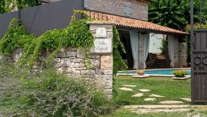 A stone wall with a sign reading "Villa Pakich" and a stone building with a tiled roof in the background. - Nice home in Sveti Lovrec (Sveti Lovrec)