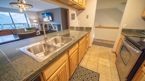 A modern kitchen with granite countertops, wooden cabinets, a stainless steel sink, and a built-in oven. - Saints John 2537 (Keystone)