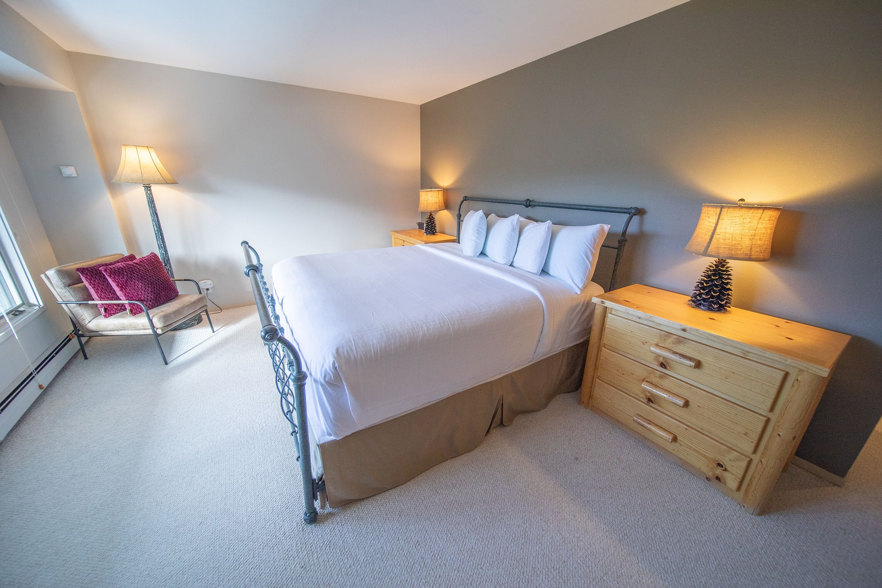 Ein Schlafzimmer mit Bett, Nachttischen, einem Sessel und einer Kommode.