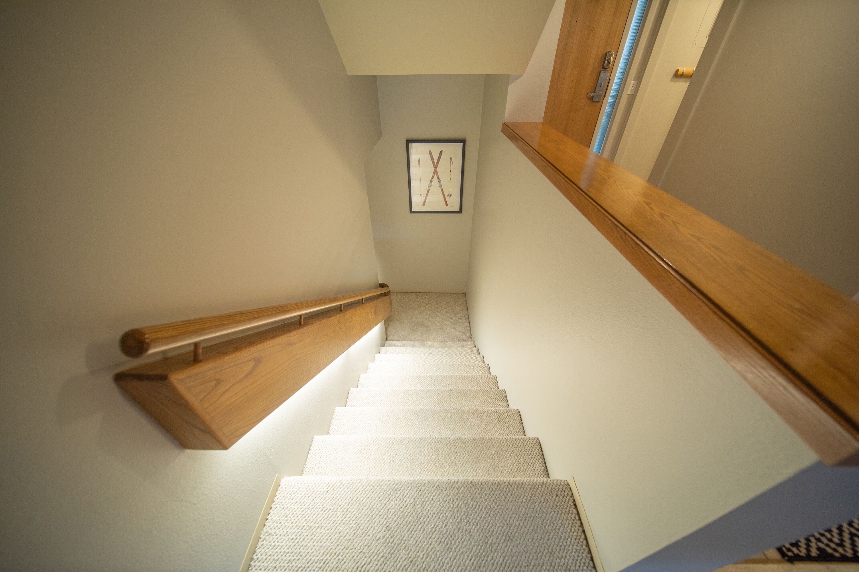 A staircase with a wooden handrail and carpeted steps leading to a landing.