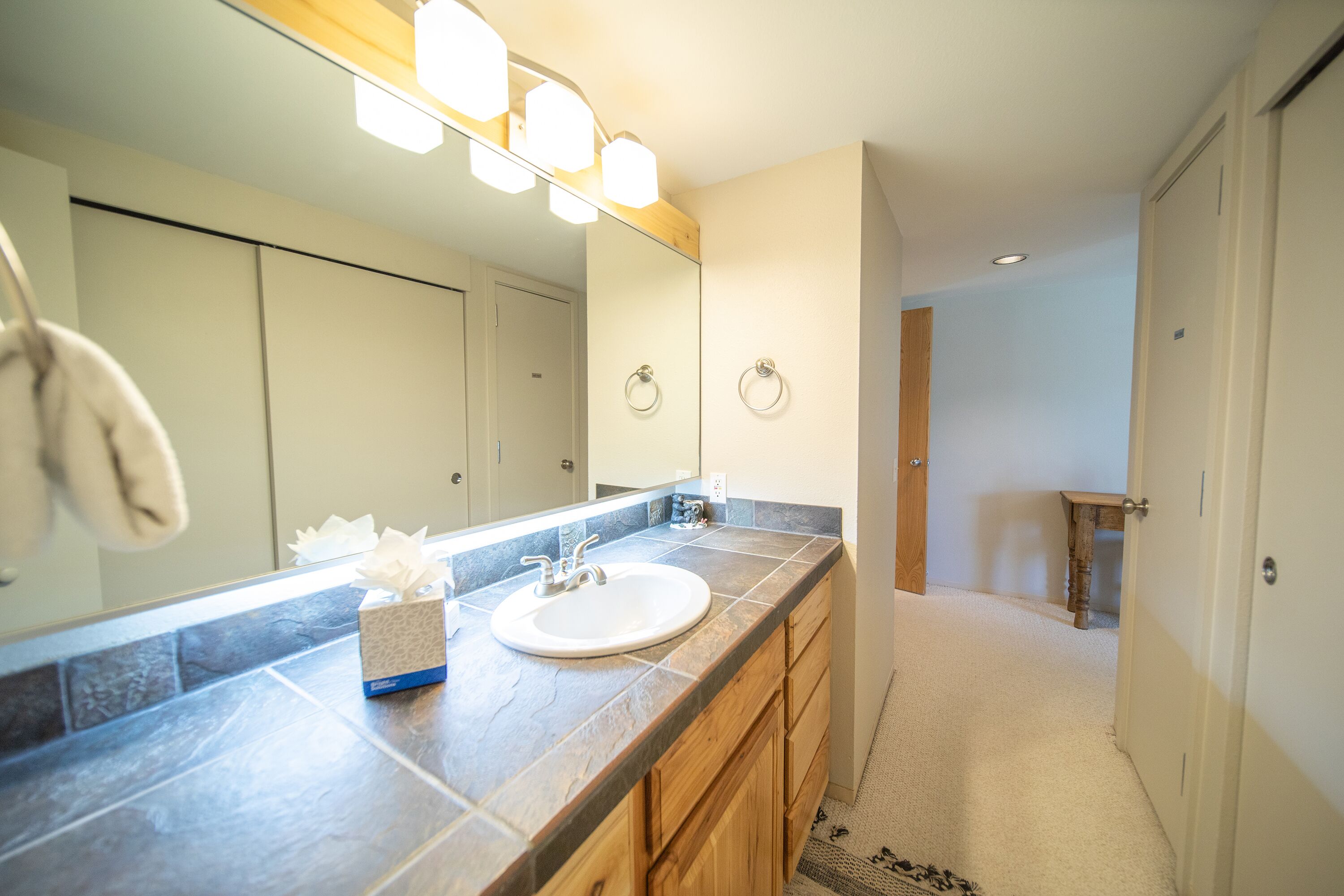 A modern bathroom with a large mirror, a sink, and a towel rack.