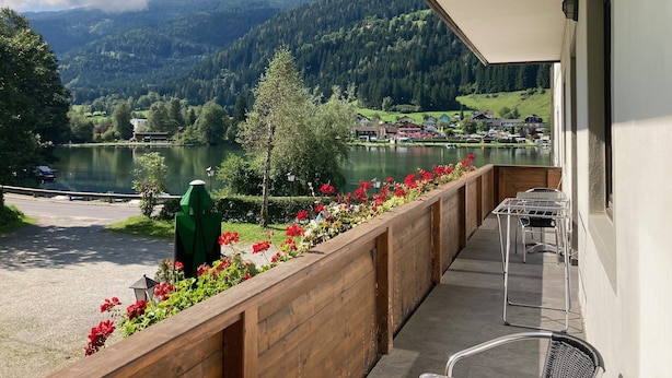 A balcony with a view of a lake, mountains, and a village. - Studio Apartment mit Balkon, am See mit Privat Badestrand. Haustierfreundlich! (Afritz)