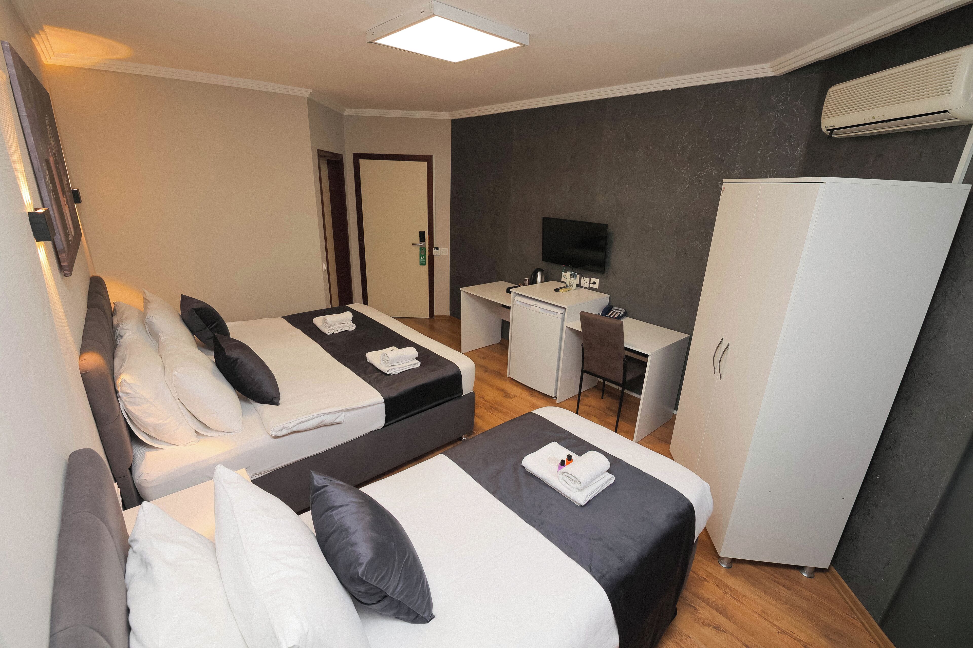 A hotel room with two beds, a desk, a TV, and a wardrobe.