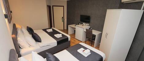 A hotel room with two beds, a desk, a TV, and a wardrobe.