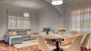 A modern living room with a grey sofa, a dining table with chairs, and a patterned floor. - Villa Rosa, a Home in Madeira (Funchal)