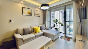 A modern living room with a sofa, a coffee table, and a large window with a view of buildings.