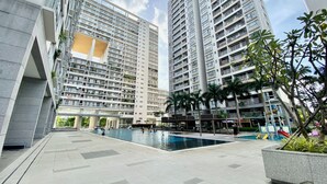A modern residential building complex with a swimming pool and outdoor seating area.