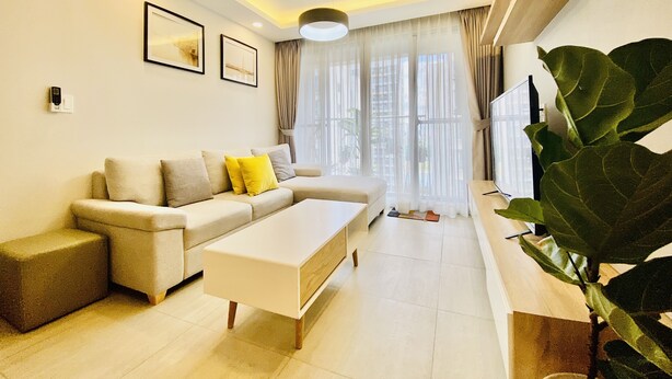 A modern living room with a sofa, a coffee table, and a large plant.