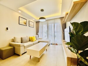 A modern living room with a sofa, a coffee table, and a large plant.