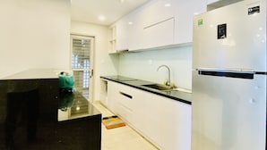 A modern kitchen with white cabinets, a black countertop, and a stainless steel refrigerator.
