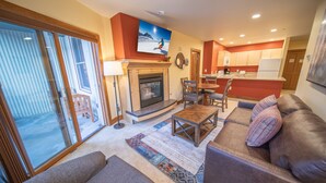 A living room with a fireplace, a sofa, a coffee table, and a television mounted on the wall. - Silver Mill 8232 (Keystone)