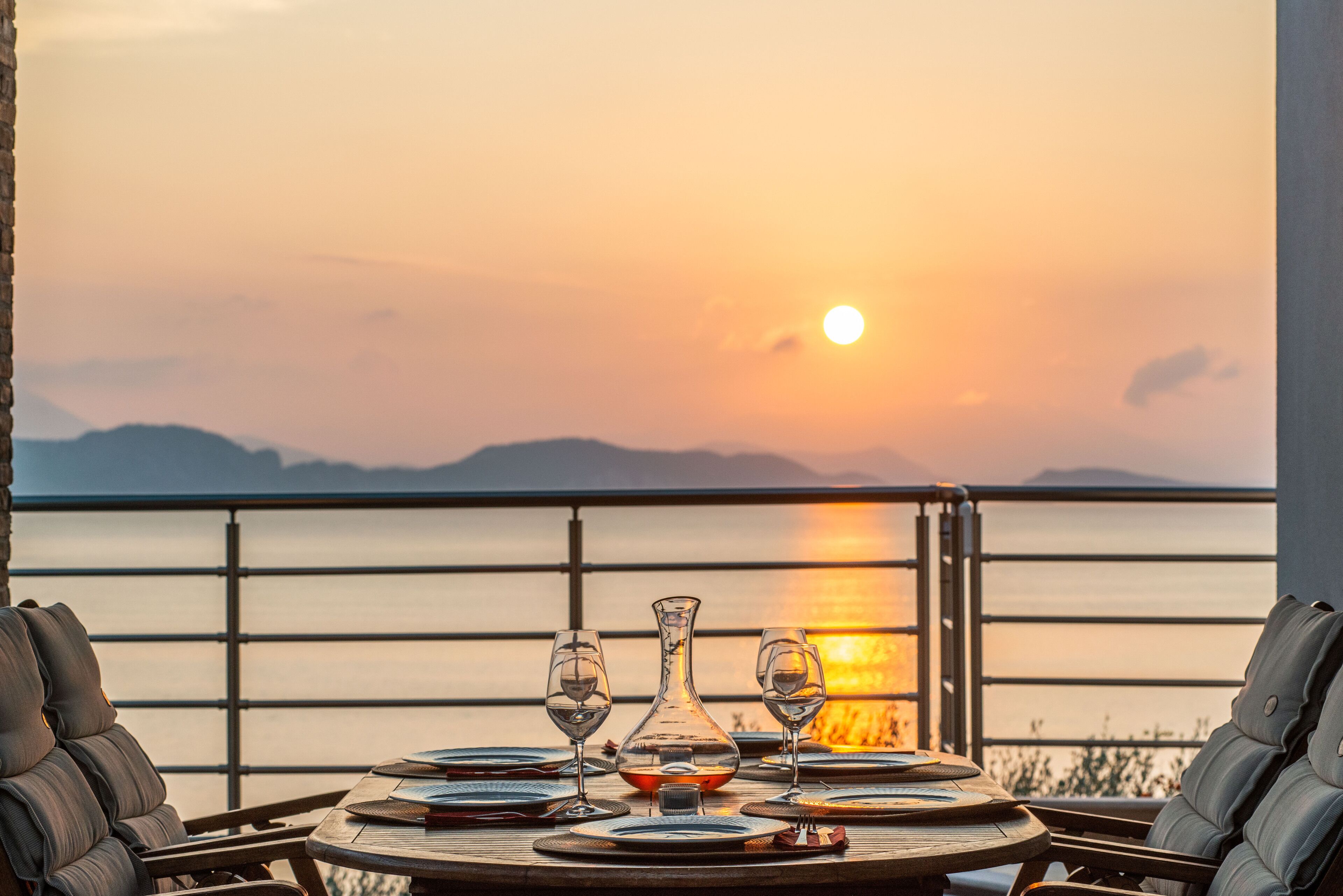 A table set for two with a view of the sunset over the water.