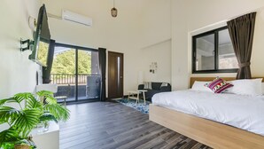 Et moderne hotelværelse med en stor seng, et skrivebord og en balkon.