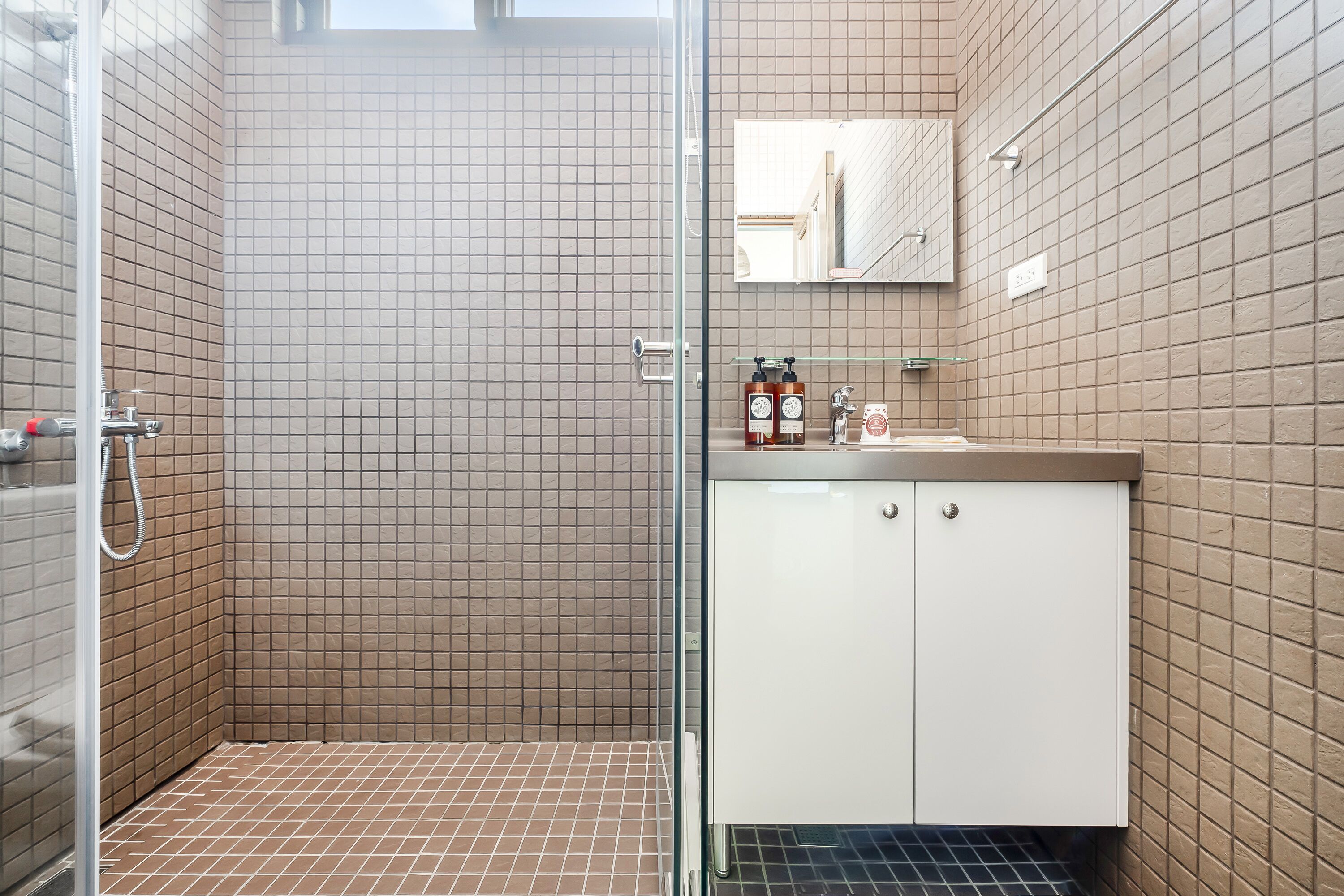 A bathroom with a shower, a sink, and a mirror.