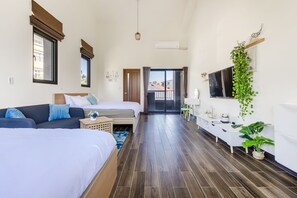 Una habitación de hotel moderna con una cama grande, un sofá, un escritorio y un televisor.