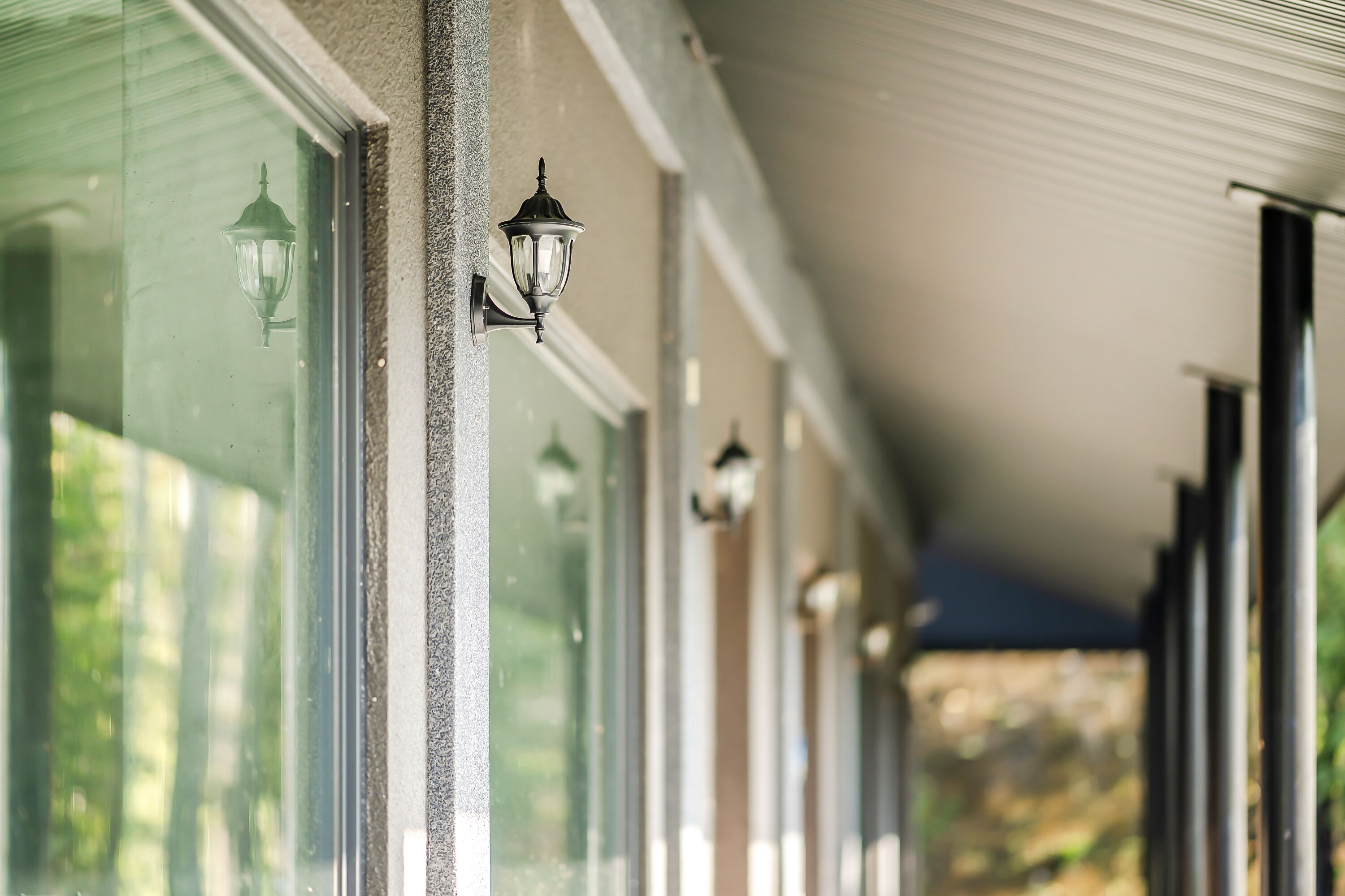 A covered corridor with windows and wall-mounted lights.
