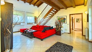 A spacious living room with a red sofa, a coffee table, and a staircase leading to another level. - Pet friendly home in Visnjan with WiFi (Visnjan)