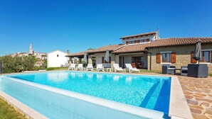 A swimming pool with lounge chairs and a stone patio. - Pet friendly home in Visnjan with WiFi (Visnjan)
