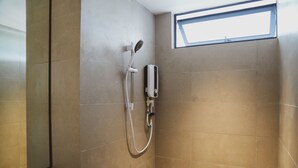 A shower with a handheld showerhead and a wall-mounted control panel, a window, and tiled walls. - Roxy Beach Apartment (Lundu)