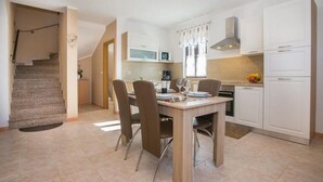 A modern kitchen with white cabinets, a dining table set for four, and a staircase leading to another level. - Beach front home in Tar-Vabriga (Tar-Vabriga)