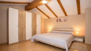 A bedroom with a bed, wooden wardrobe, bedside lamps, and a small rug. - Beach front home in Tar-Vabriga (Tar-Vabriga)