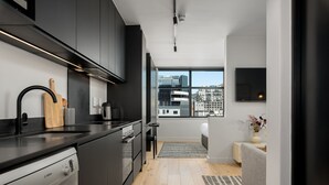 A modern kitchen with a dishwasher, a wooden cutting board, and a coffee machine.