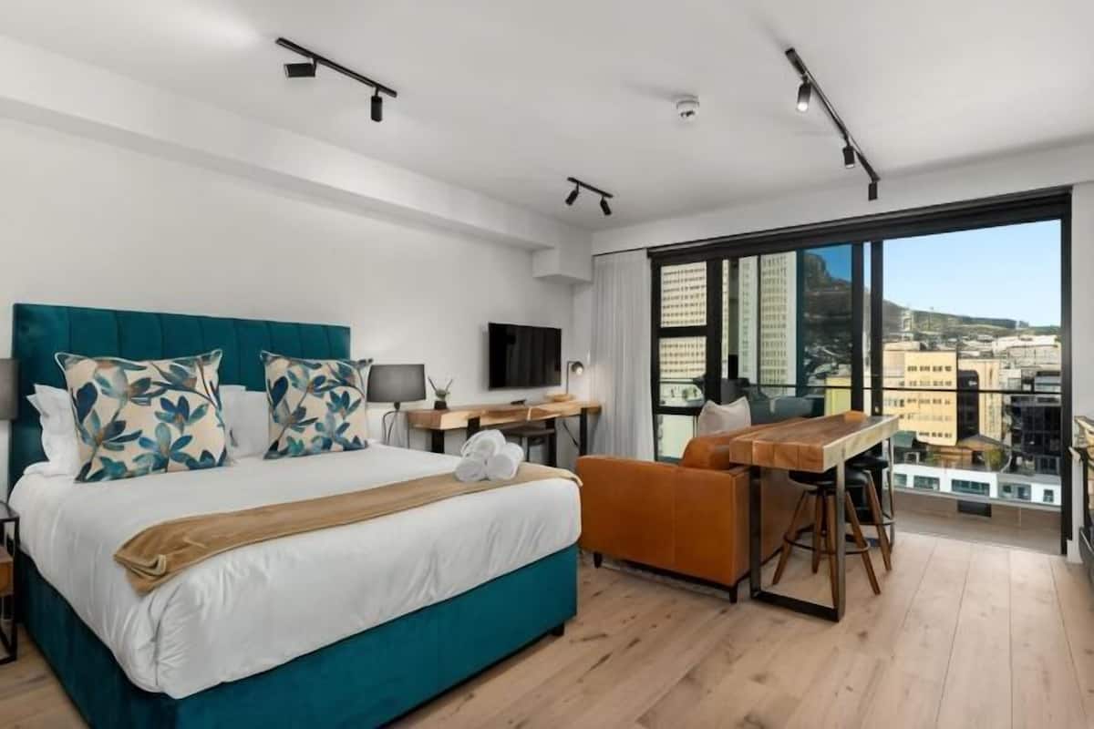 Een moderne slaapkamer met een groot bed, een bureau en uitzicht op de stad.