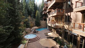 A hotel courtyard with a swimming pool, outdoor seating, and a stone wall. - Timbers 3080 (Keystone)
