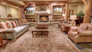 A cozy living room with a stone fireplace, leather sofas, and a patterned rug. - Timbers 3080 (Keystone)