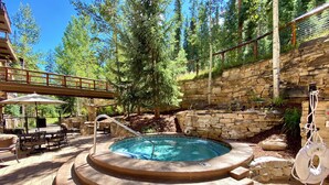 A hot tub with a stone wall and a wooden deck with outdoor furniture. - Timbers 3080 (Keystone)