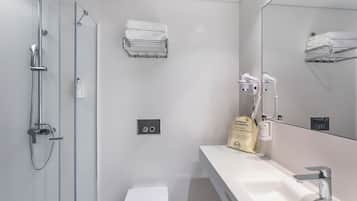A modern bathroom with a shower, toilet, and sink. There are towels and toiletries on the counter.
