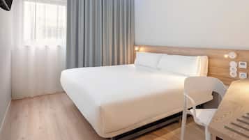 Une chambre d’hôtel avec un lit, un bureau et une chaise.