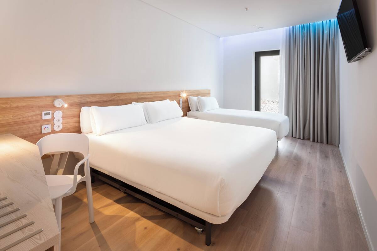 A modern hotel room with a large bed, a desk, and a chair.