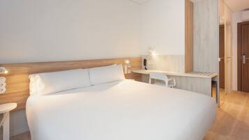 Quarto de hotel moderno com uma cama grande, uma escrivaninha e uma cadeira.