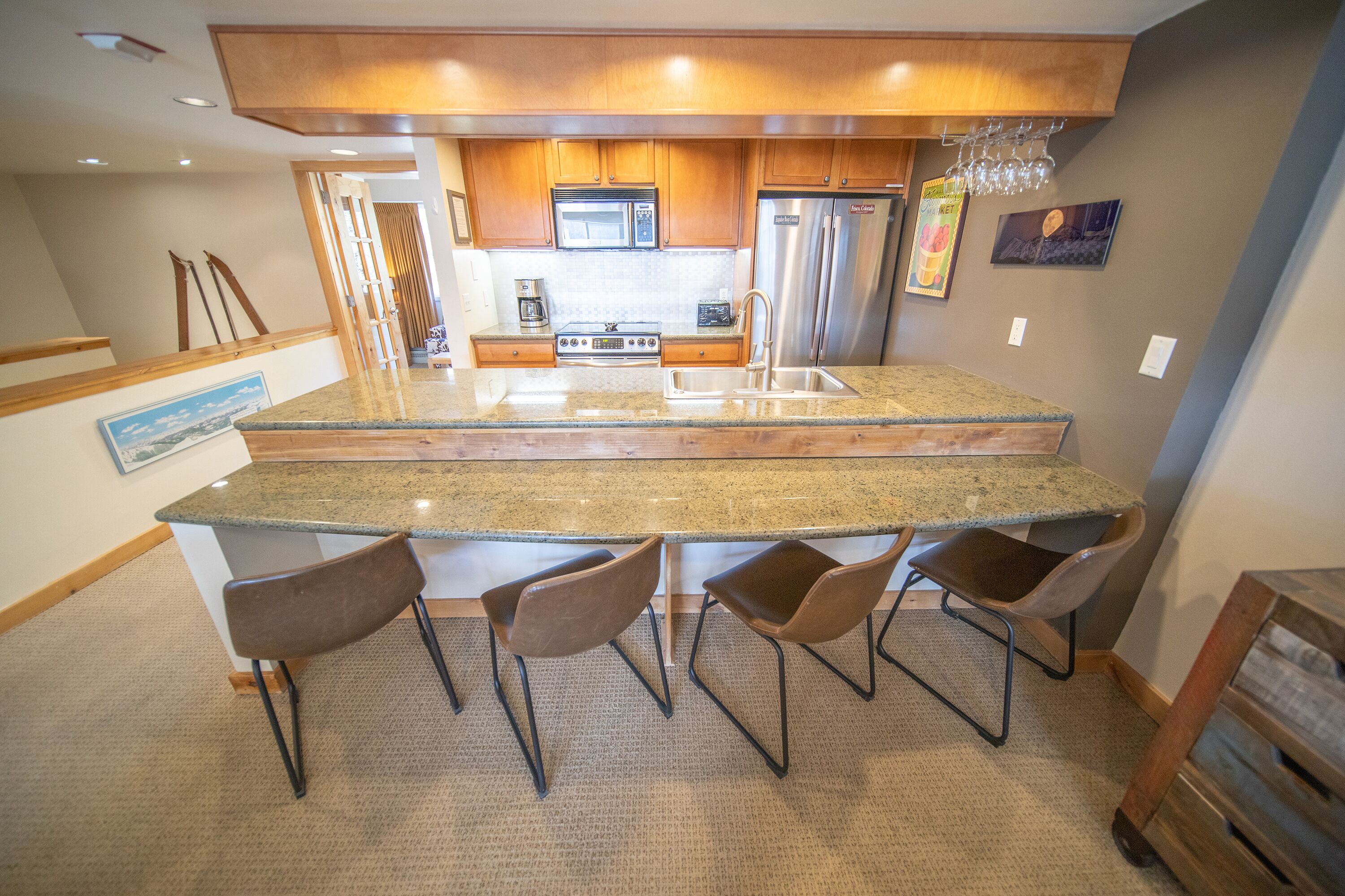 A kitchen with granite countertops, stainless steel appliances, and a central island with bar stools.