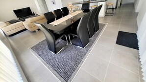 Een moderne woonkamer met een bank, een televisie en een eethoek met een tafel en stoelen.