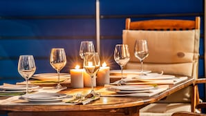 A table set for dining with candles, glasses, and plates. - Seafront Marine Villa: Seaside Elegance, 30m from the Shore (Sivota)